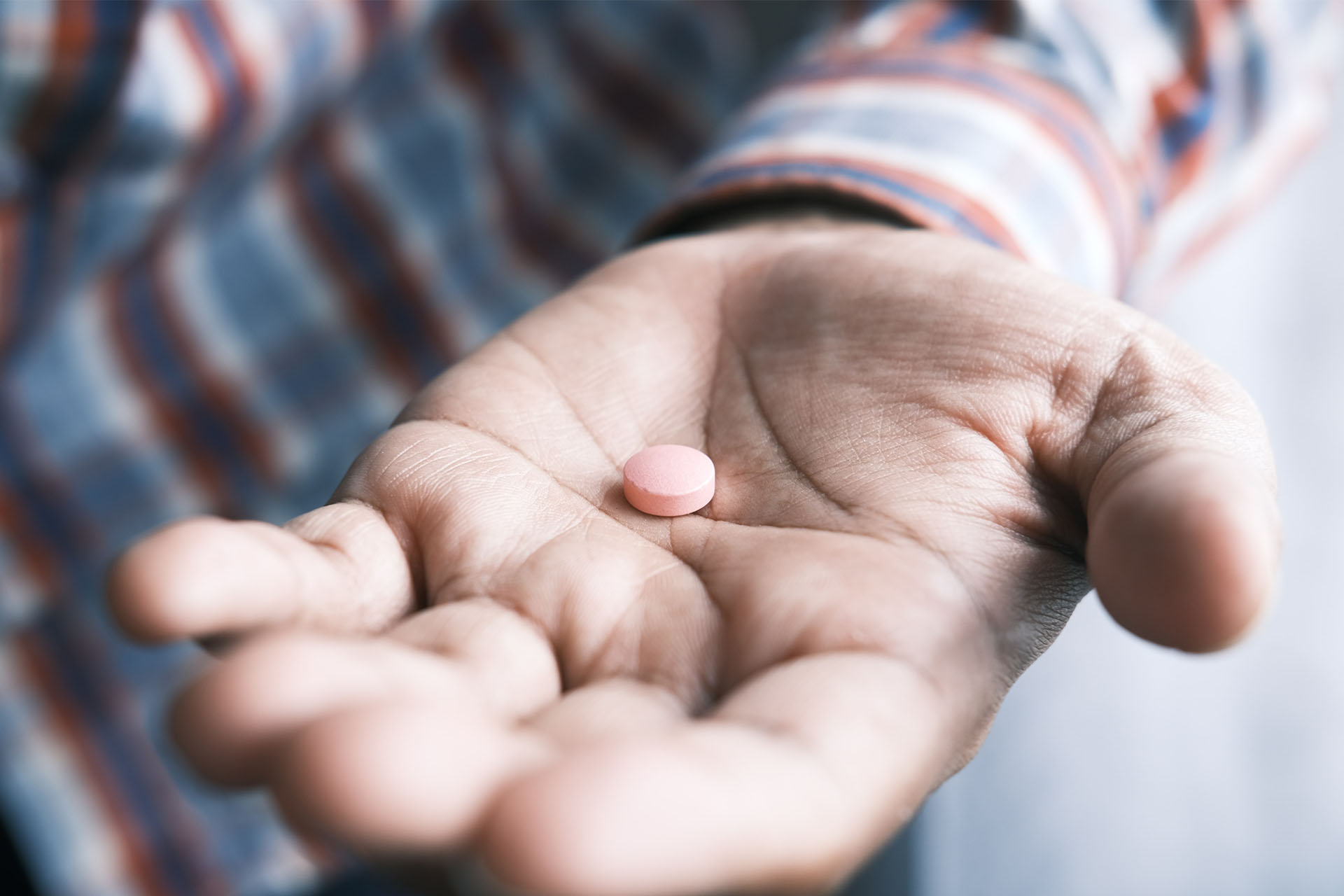 Man holding a pink pill in his hand